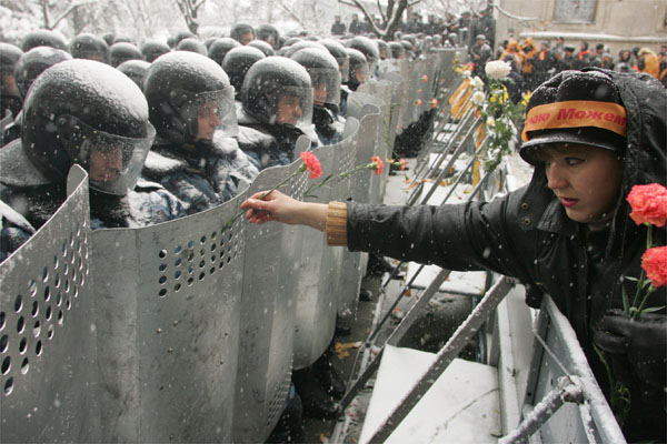 A woman places flowers in riot policemen's shields outside the presidential office in Kiev, Ukraine, November 24, 2004. Reuters